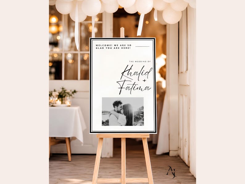 A wedding welcome sign for Khalid and Fatima displayed on a wooden easel indoors with white paper lanterns hanging overhead.