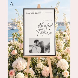 A wedding welcome sign for Khalid and Fatima on an easel outdoors with a water backdrop and abundant white and pink roses.