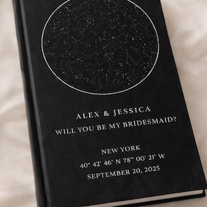 May include: A black book with a white circle containing a star map. The text reads "ALEX & JESSICA WILL YOU BE MY BRIDESMAID? NEW YORK 40° 42' 46' N 78° 00' 21' W SEPTEMBER 20, 2025."