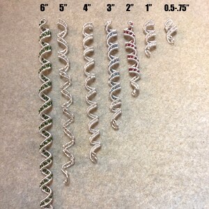 May include: A set of silver hair cuffs in various lengths, ranging from 0.5 to 6 inches. The cuffs are decorated with small green, blue, and red beads.