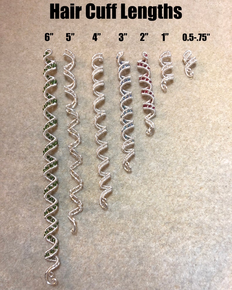 May include: A set of silver hair cuffs in various lengths, ranging from 0.5 to 6 inches. The cuffs are decorated with small green, blue, and red beads.