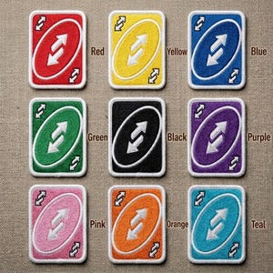 May include: Nine colorful embroidered patches resembling Uno reverse cards. The patches are in red, yellow, blue, green, black, purple, pink, orange, and teal. Each card features a white arrow design and a white border.