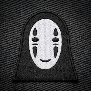 May include: Black and white embroidered patch featuring the character No-Face from the animated film Spirited Away. The patch has a black background with a white face and black details, including eyes and a smiling mouth. The patch is rectangular with rounded top.