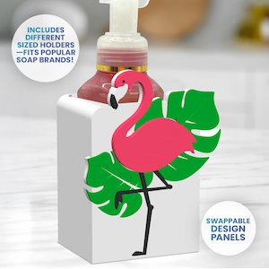May include: A white soap dispenser holder with a pink flamingo and green leaf design. The holder has the text "INCLUDES DIFFERENT SIZED HOLDERS - FITS POPULAR SOAP BRANDS!" and "SWAPPABLE DESIGN PANELS". A pink soap bottle is inside the holder.
