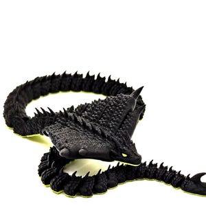 Könnte beinhalten: Eine schwarze Drachenskulptur mit strukturiertem Körper und gelben Akzenten. Der Drache hat einen detaillierten Kopf mit spitzen Hörnern und leuchtend gelben Augen. Der Schwanz der Skulptur ist geschwungen und erzeugt ein dynamisches Design.