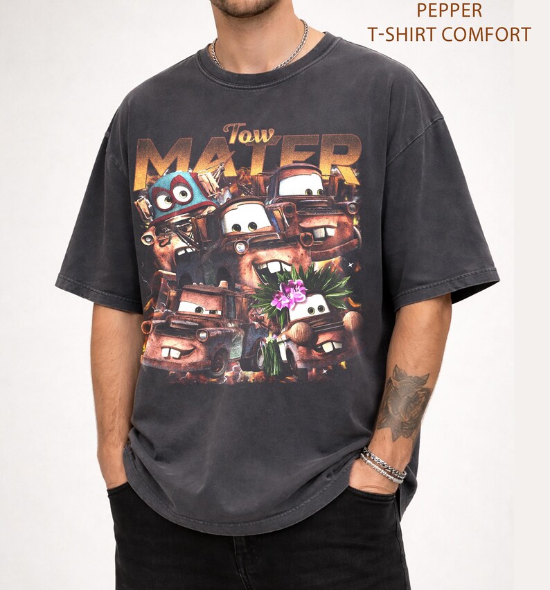 Puede incluir: Camiseta gris oscuro con un dise&ntilde;o del personaje Tow Mater de la pel&iacute;cula Cars. El dise&ntilde;o incluye el texto "Tow Mater" en una fuente desgastada, con im&aacute;genes del personaje. La camiseta est&aacute; etiquetada como "Pepper T-Shirt Comfort".