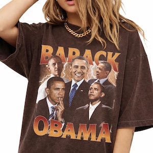 May include: Brown t-shirt featuring a collage of Barack Obama images with the text "BARACK OBAMA" in orange and yellow. The shirt has a vintage, distressed look.