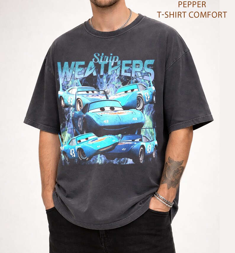 May include: Dark gray t-shirt featuring a graphic of blue race cars with the text "Strip Weathers". The cars have the number 43 on them. The shirt has a vintage, distressed look and the text "Pepper T-Shirt Comfort" is printed on the top right.