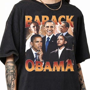 May include: Black t-shirt featuring a collage of images of Barack Obama, with the word "BARACK" in orange and red block letters above the images. The word "OBAMA" is printed in orange and red block letters below the images.
