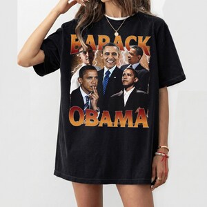 May include: Black t-shirt featuring a collage of Barack Obama images with the text "BARACK OBAMA" in orange and yellow. The shirt has a vintage, distressed look.