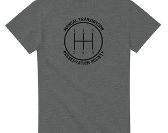 May include: Dark gray t-shirt featuring a black graphic of a manual transmission gear shift pattern. The text around the gear shift reads "Manual Transmission Preservation Society". The shirt is made of a soft, comfortable material.