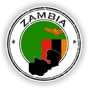 Op de afbeelding: Een versleten, ronde stempel met het woord "ZAMBIA" in zwarte letters rond de rand. Het midden van de stempel toont de Zambiaanse vlag met een zwarte omtrek van de kaart van het land.
