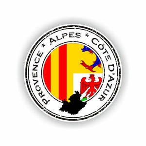 Può includere: Un timbro circolare usurato con il testo "Provence * Alpes * Côte D'Azur" in lettere nere attorno al bordo. Il centro del timbro presenta la bandiera della Provenza-Alpi-Costa Azzurra, un campo giallo con tre strisce verticali rosse, e una silhouette nera della regione.