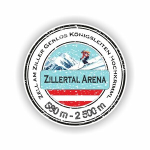 May include: Circular sticker with a black border. It features the text "Zell am Ziller Gerlos Königsleiten Hochkrimml" and "Zillertal Arena". The sticker shows a skier, mountains, and the Austrian flag. The elevation range is 580 m - 2500 m.