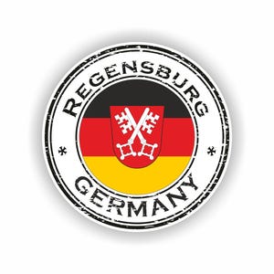 Könnte beinhalten: Ein runder Aufkleber mit dem Stadtnamen "Regensburg" und "Germany" in einer verwitterten Schriftart. Das Design beinhaltet die Farben der deutschen Flagge und ein Wappen mit gekreuzten Schlüsseln.