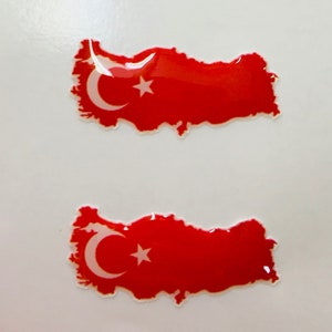 May include: Two red and white Turkish flag stickers in the shape of Turkey. The stickers are glossy and have a 3D effect.
