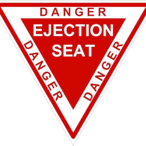 Puede incluir: Una señal de advertencia triangular roja con letras blancas. La señal dice "DANGER EJECTION SEAT DANGER" con la palabra "DANGER" repetida a cada lado del triángulo.