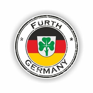以下が含まれることがあります： ドイツ国旗とフュルト市のエンブレムが描かれた丸いステッカー。エンブレムは白い背景に緑のクローバー。ステッカーには「FURTH」と「GERMANY」の文字が黒の擦れたフォントで書かれています。