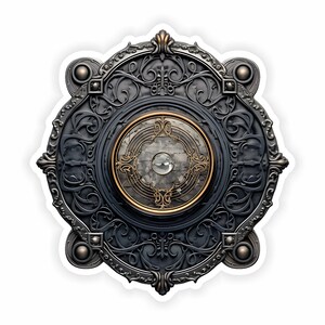May include: A circular, ornate metal design with a central, circular, gray and gold design. The metal design has a dark gray finish and gold accents. The central design has a clear crystal in the center.