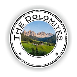 May include: A black and white circular stamp with the text "THE DOLOMITES" around the edge. The centre of the stamp features a scenic image of the Italian Dolomites mountains with a small village in the foreground.