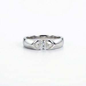 Pode incluir: Um anel de prata polida com uma pedra central de diamante em forma de marquesa. O anel tem uma banda lisa e arredondada e uma moldura de bisel que segura o diamante com segurança. O diamante parece claro e brilhante.