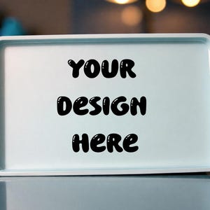 May include: A rectangular, light blue tray with rounded corners. The words "YOUR DESIGN HERE" are written in bold, black bubble letters across the center of the tray. The tray is sitting on a reflective surface.
