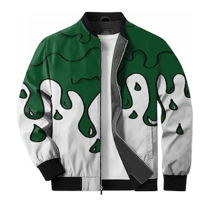 May include: A bomber jacket featuring a white base with a dark green slime drip pattern. The jacket has a black ribbed collar, black sleeve cuffs, and a black hem. A central silver zipper runs down the front, revealing a plain white shirt underneath.