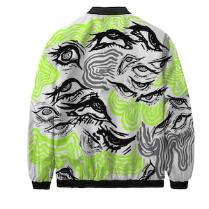 May include: White bomber jacket featuring a repeating pattern of black, stylized eyes. The design includes neon green wavy lines and gray, organic shapes. The jacket has a black collar, cuffs, and hem.