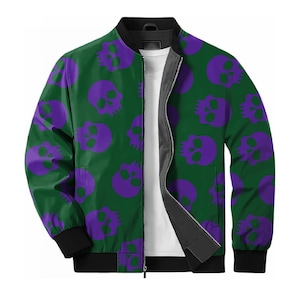 May include: A bomber jacket featuring a dark green base color with a repeating pattern of purple skulls. The jacket has a black ribbed collar, black cuffs, and a black hem, with a silver-toned metal zipper running down the center front.