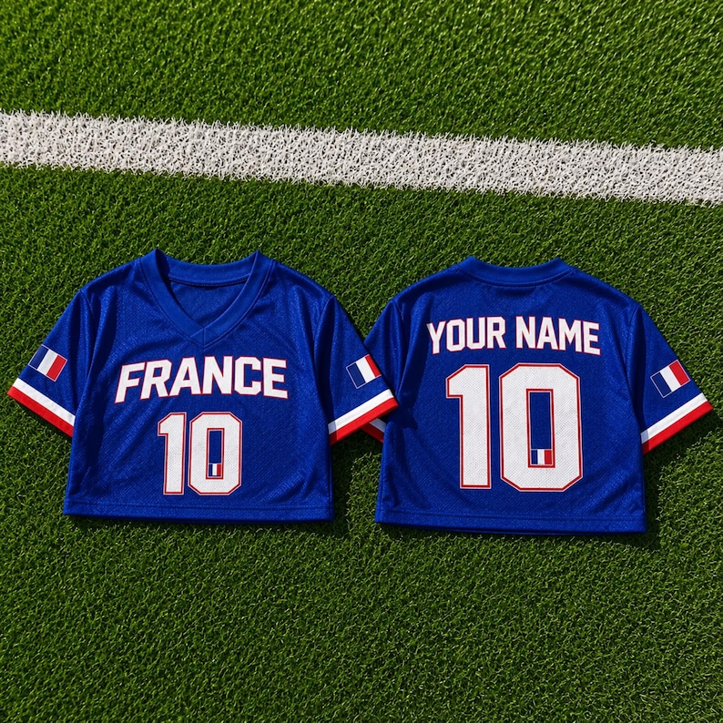 May include: Two blue mesh crop tops with white lettering and the number 10. One top says "FRANCE" and the other says "YOUR NAME". Each has a French flag on the sleeve and is on a green surface.