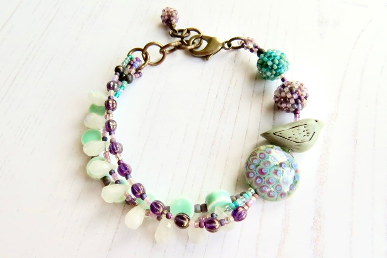 Crocus handmade artisan bead bracelet in deep purple and fresh turquoise with bird detail Songbead, UK, narrative jewelry image 3