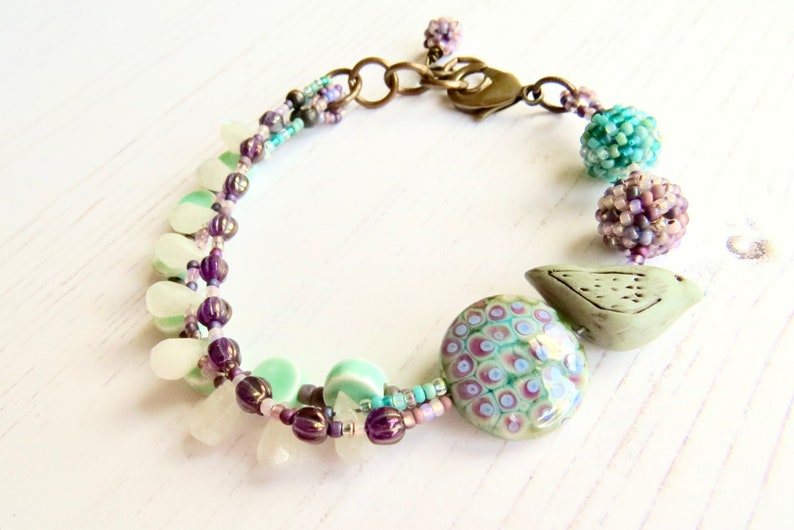 Crocus handmade artisan bead bracelet in deep purple and fresh turquoise with bird detail Songbead, UK, narrative jewelry image 5