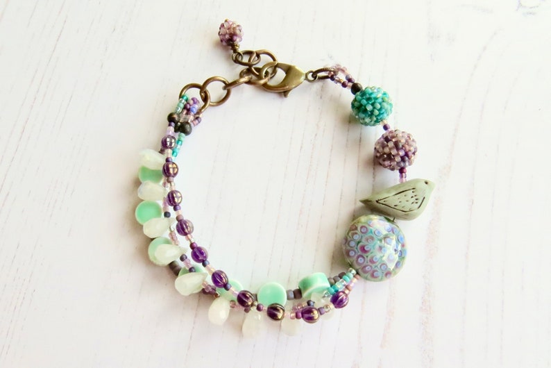 Crocus handmade artisan bead bracelet in deep purple and fresh turquoise with bird detail Songbead, UK, narrative jewelry image 2