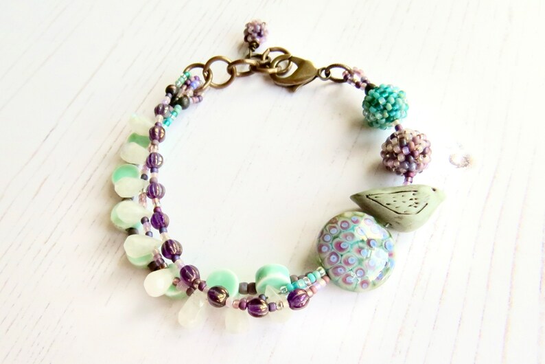 Crocus handmade artisan bead bracelet in deep purple and fresh turquoise with bird detail Songbead, UK, narrative jewelry image 6