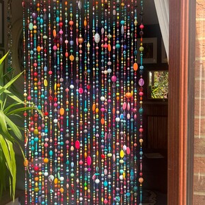 Pu&ograve; includere: Una tenda di perline con una vibrante gamma di colori, tra cui rosso, arancione, giallo, verde, blu e viola. Le perline sono di varie forme e dimensioni, creando un accento decorativo e accattivante per la porta.