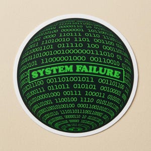 May include: Round black coaster with a green binary code pattern. The words "SYSTEM FAILURE" are in a green rectangular box in the center. The coaster has a white border.