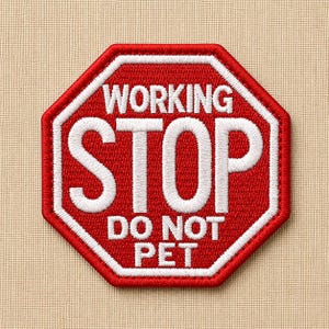 May include: Embroidered red and white patch in the shape of a stop sign. The patch reads "WORKING STOP DO NOT PET" in white capital letters. The patch has a white border and is on a tan fabric background.