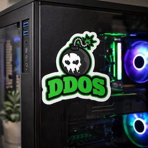 May include: A sticker featuring a black bomb with a skull design and the word "DDOS" in green. The sticker is affixed to a black computer case. The computer case has a glass side panel, revealing internal components with colorful LED lighting.