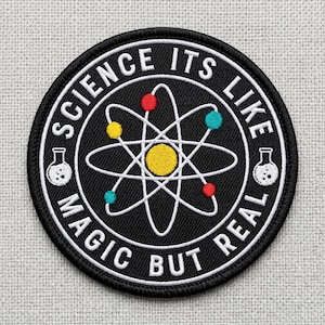 May include: A white ceramic mug with a black handle and the text "But First, Coffee" in a black, handwritten-style font. The mug is on a white surface.