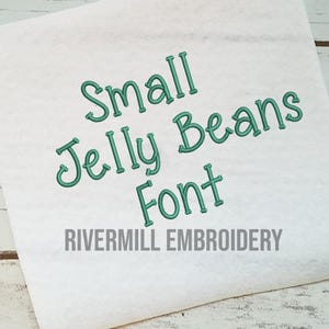 May include: A white fabric swatch with the text "Small Jelly Beans Font" in green embroidery and the text "Rivermill Embroidery" in gray below.