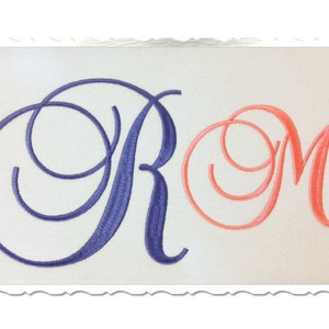May include: Two embroidered letters, "R" and "M", in a cursive font. The "R" is blue and the "M" is pink.