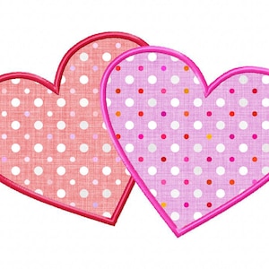 May include: Two pink and red hearts with white polka dots. The hearts are overlapping and have a stitched outline.
