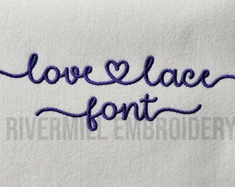 May include: Embroidered font design that says "love lace font" with a heart in place of the "o" in love. The text is in a cursive style and is embroidered in purple thread on a white background.