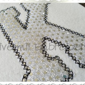 May include: A silver sequin letter K with a black stitched border. The letter is on a white background.