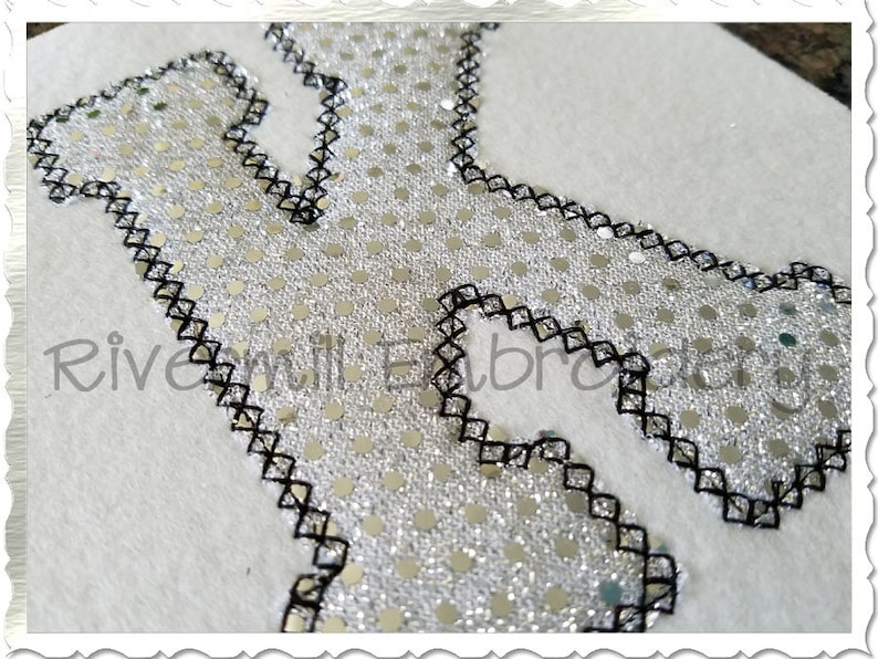 May include: A silver sequin letter K with a black stitched border. The letter is on a white background.