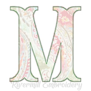 Peut inclure: Une grande lettre M blanche avec un motif paisley dans des tons de rose, bleu et vert. La lettre est soulignée en vert et a un aspect cousu.