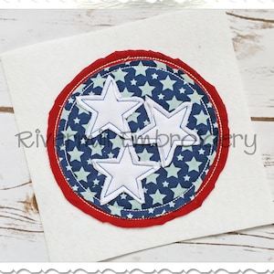 May include: A red, white, and blue fabric applique with three white stars in the center. The stars are surrounded by a blue fabric with white stars printed on it. The applique is surrounded by a red fabric border.