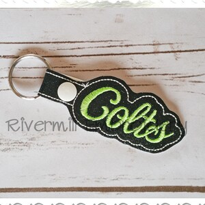 May include: Black and green key chain with the word "Colts" embroidered in green.