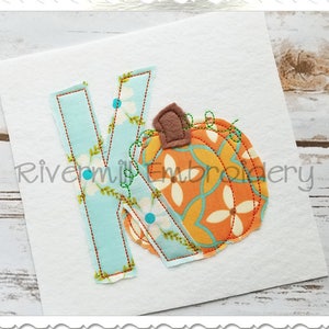 May include: A light blue fabric letter K with a small orange and brown pumpkin applique. The pumpkin has a white and orange floral pattern.