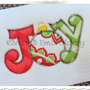 May include: A red, green, and yellow applique of the word "Joy" with a Christmas ornament in the center. The ornament is decorated with a green and red floral pattern.